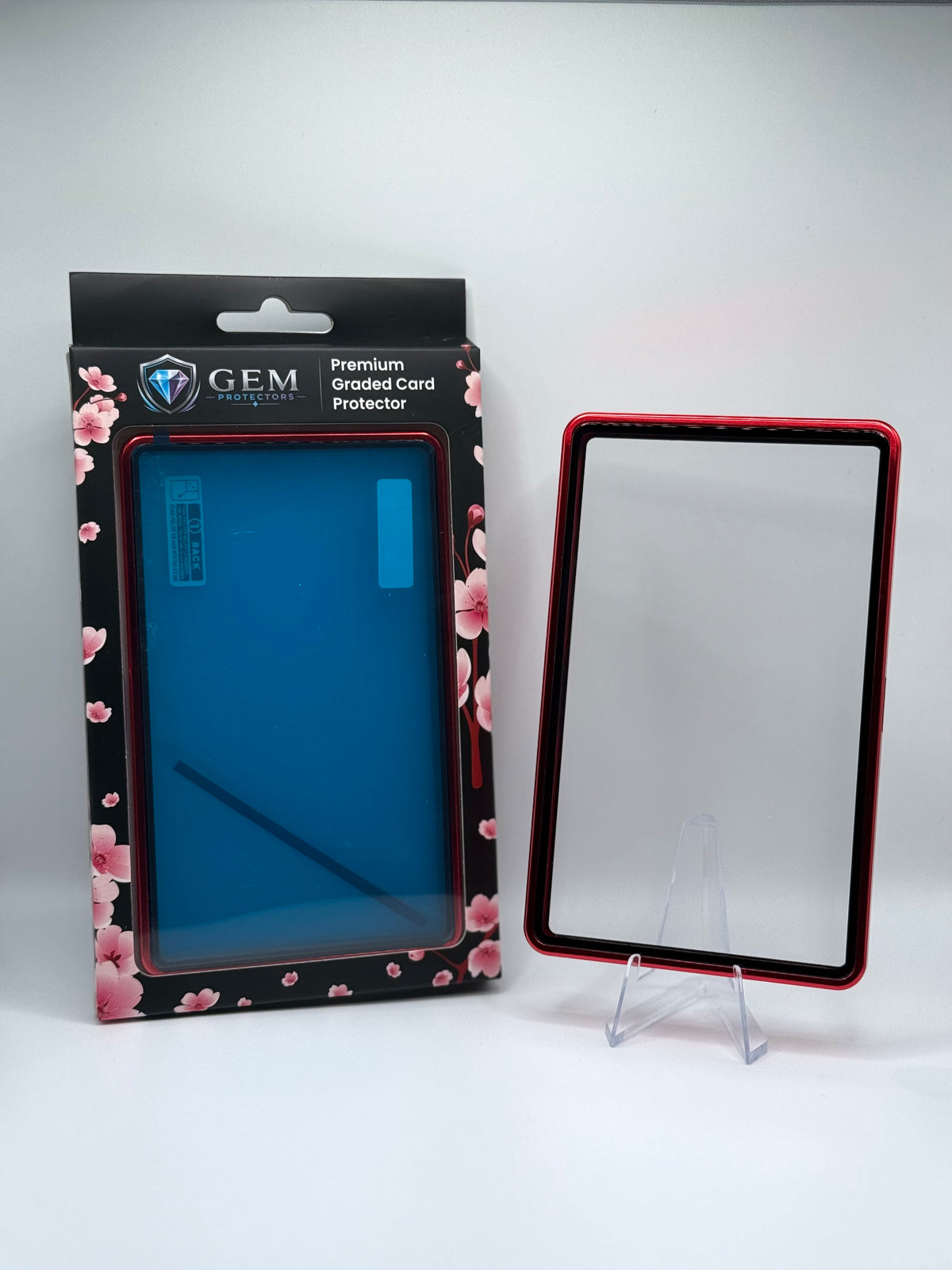 Front view of the empty Red Gem Protectors case showing the frame and clear panel, beside its retail box