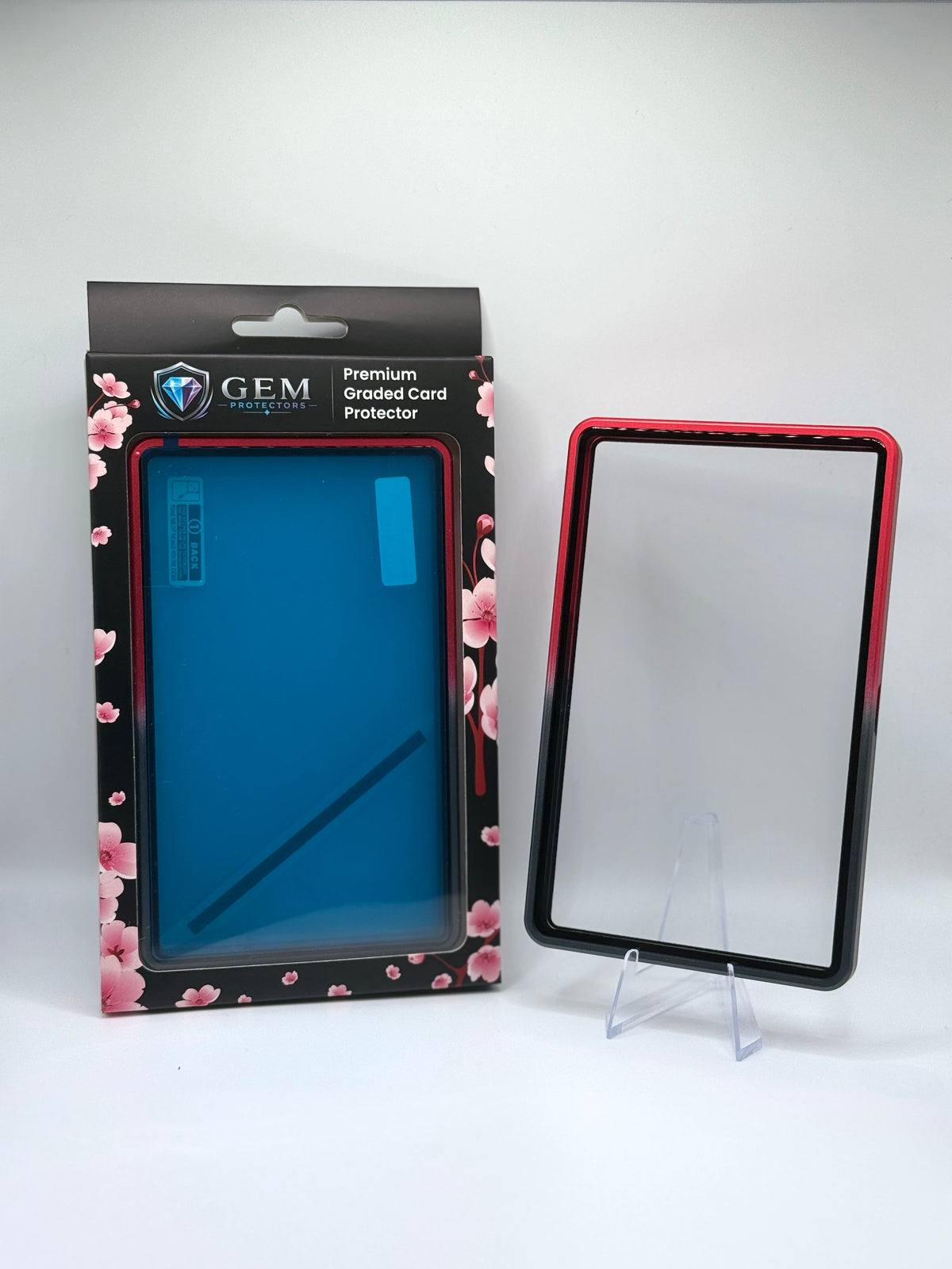 Front view of the empty Black & Red Gem Protectors case showing the frame and clear panel, beside its retail box