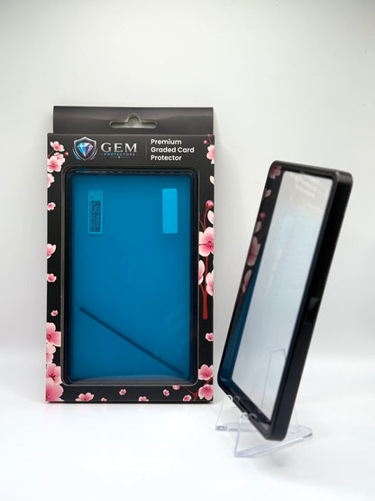 Black Gem Protectors case angled on a clear stand to show the frame's side profile, next to its retail box
