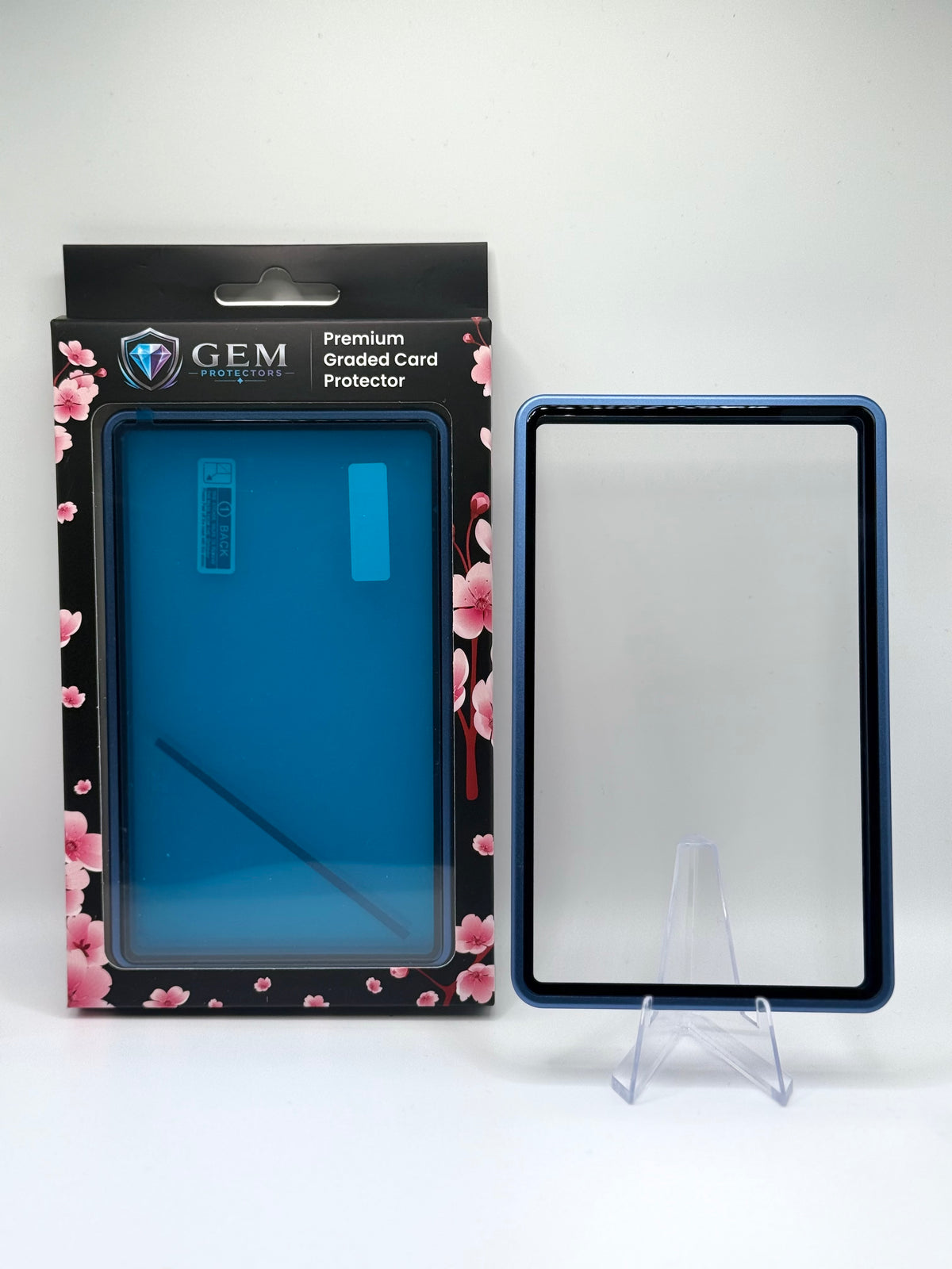 Cosmic Blue Gem Protectors magnetic PSA slab case standing upright on a clear stand next to its retail box