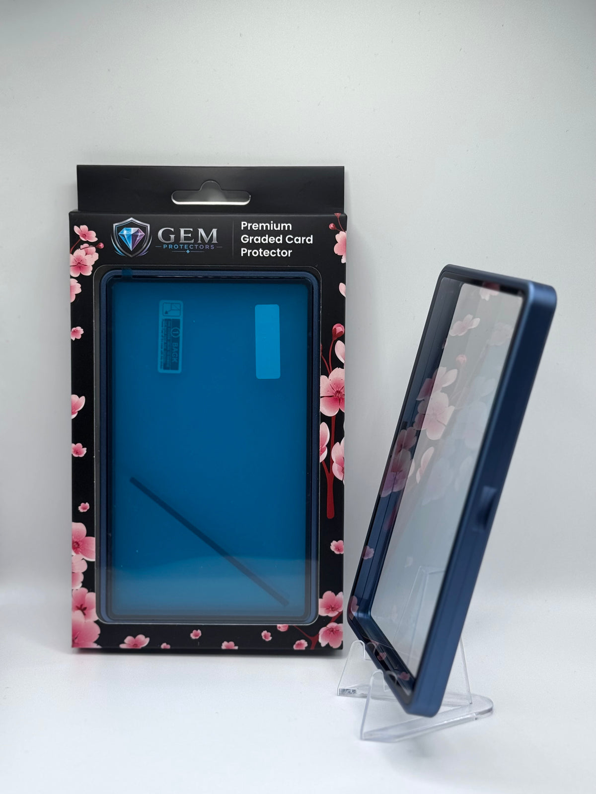 Cosmic Blue Gem Protectors case angled on a clear stand to show the frame's side profile, next to its retail box