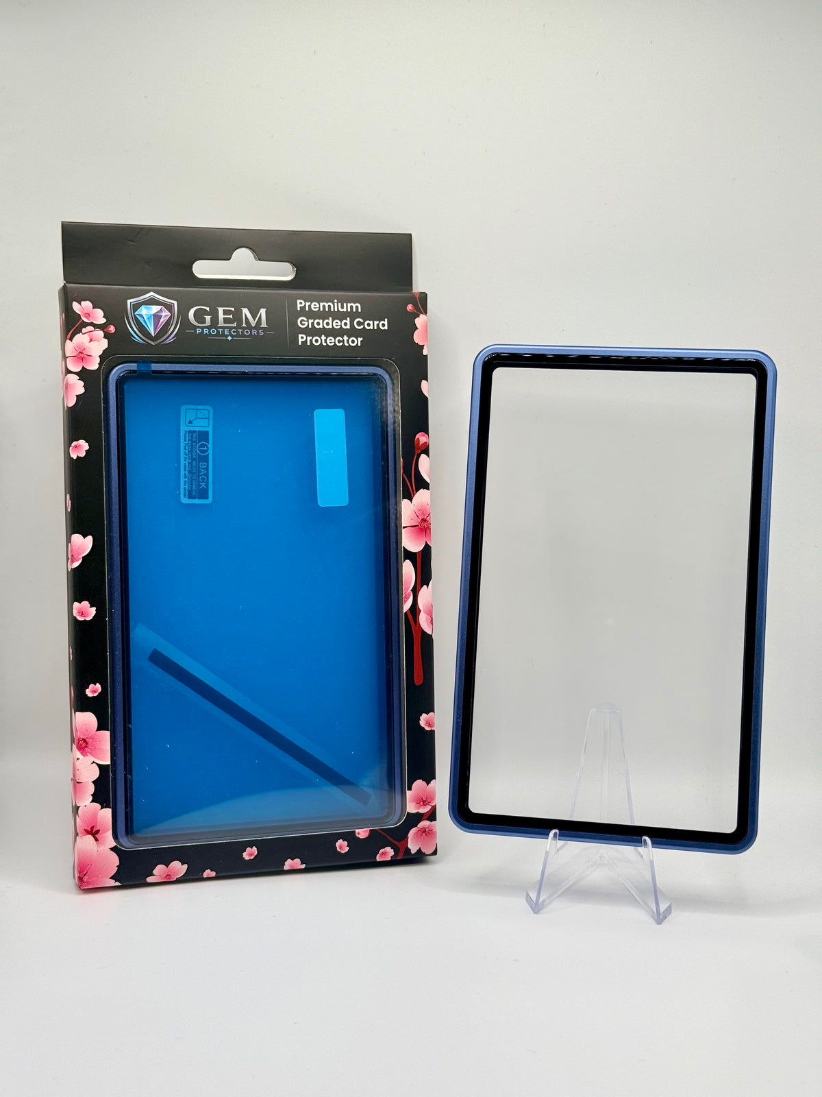 Front view of the empty Cosmic Blue Gem Protectors case showing the frame and clear panel, beside its retail box