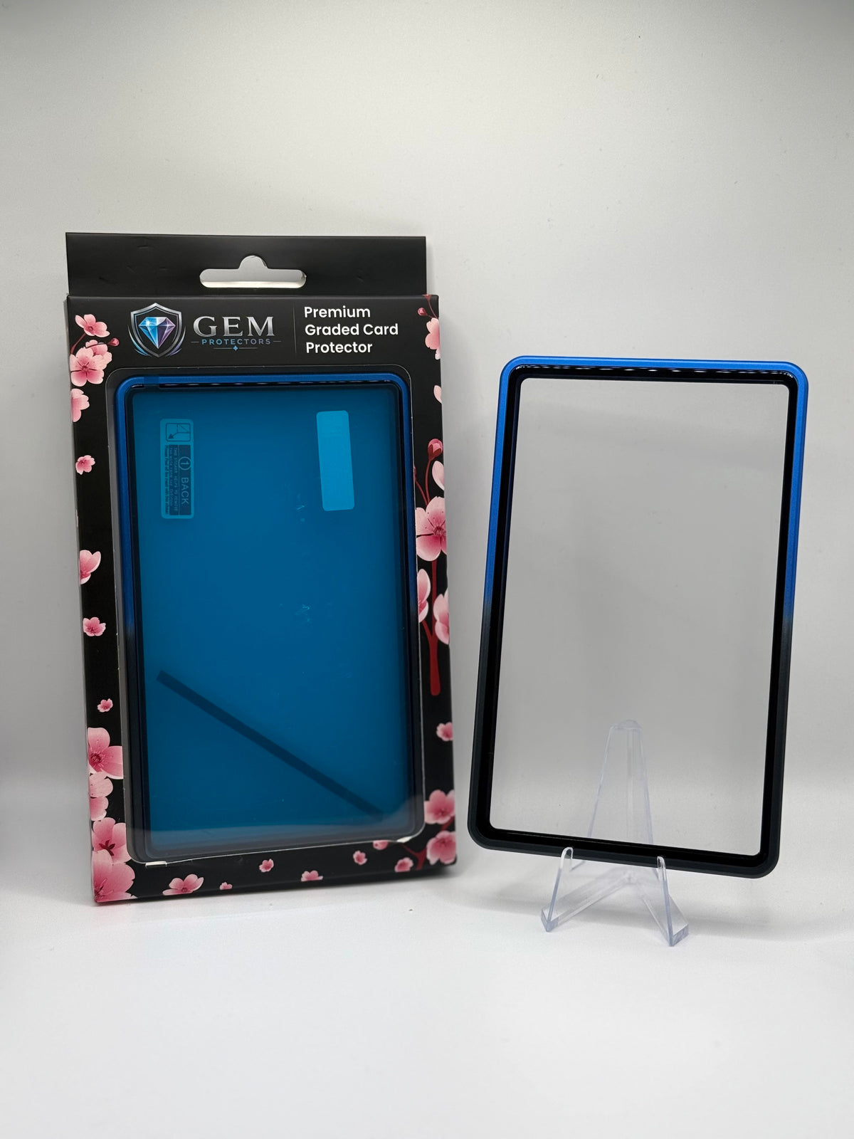 Front view of the empty Black & Blue Gem Protectors case showing the frame and clear panel, beside its retail box