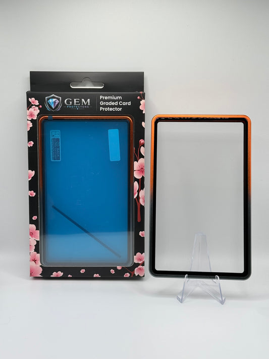Black & Orange Gem Protectors magnetic PSA slab case standing upright on a clear stand next to its retail box