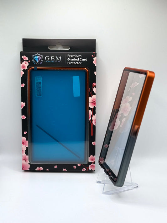 Black & Orange Gem Protectors case angled on a clear stand to show the frame's side profile, next to its retail box