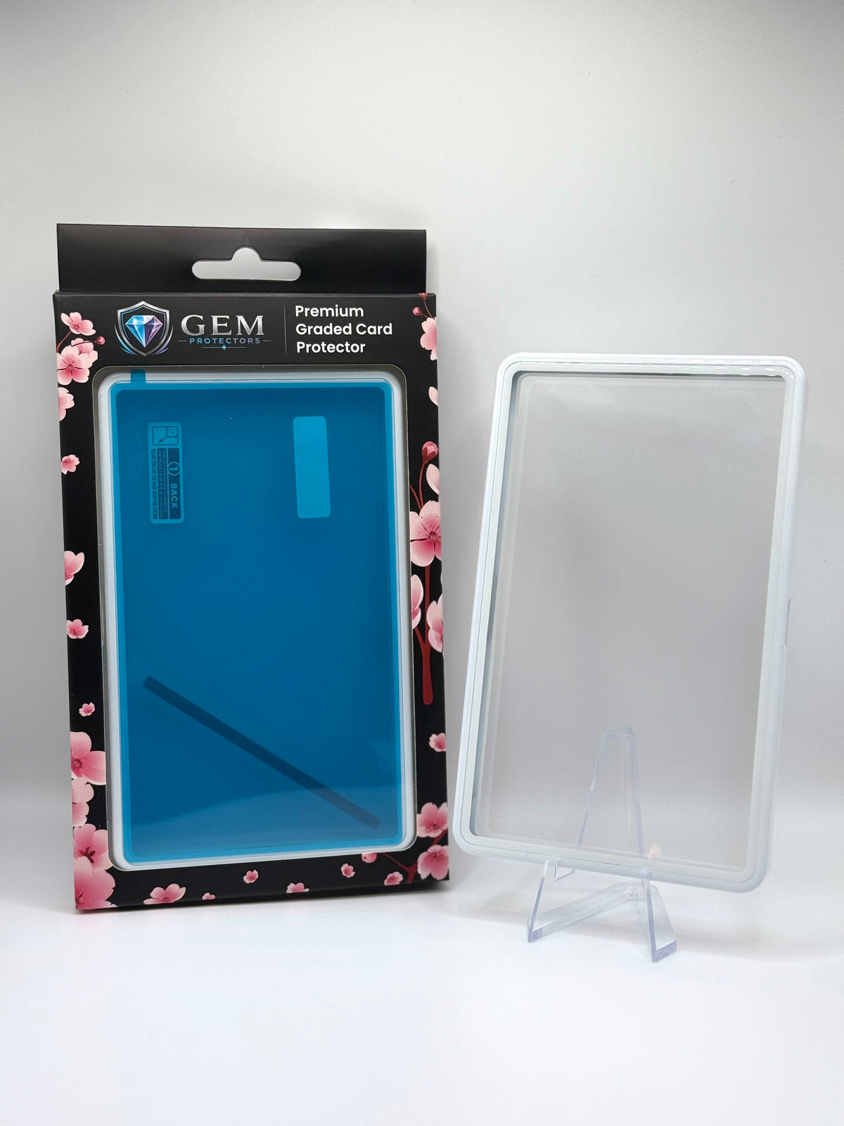 Front view of the empty Porcelain White Gem Protectors case showing the frame and clear panel, beside its retail box