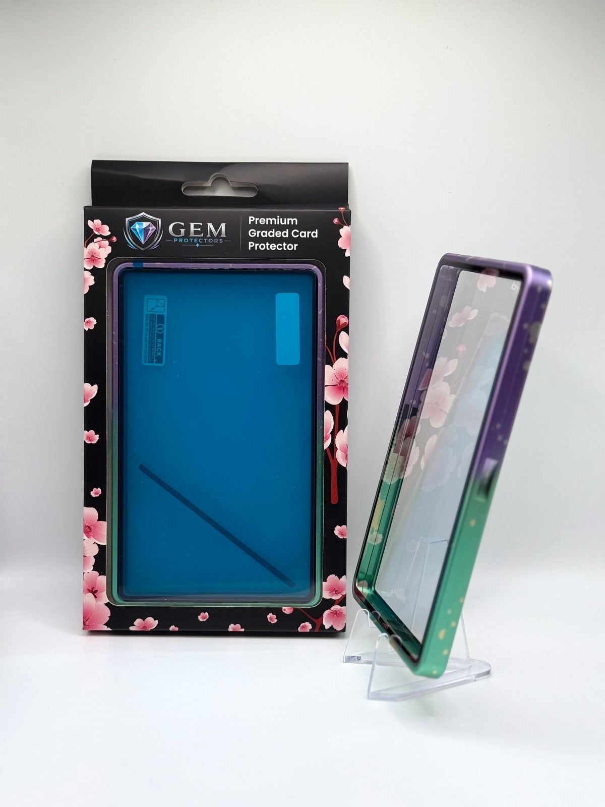 Cyan & Purple Sparkle Gem Protectors case angled on a clear stand to show the frame's side profile, next to its retail box