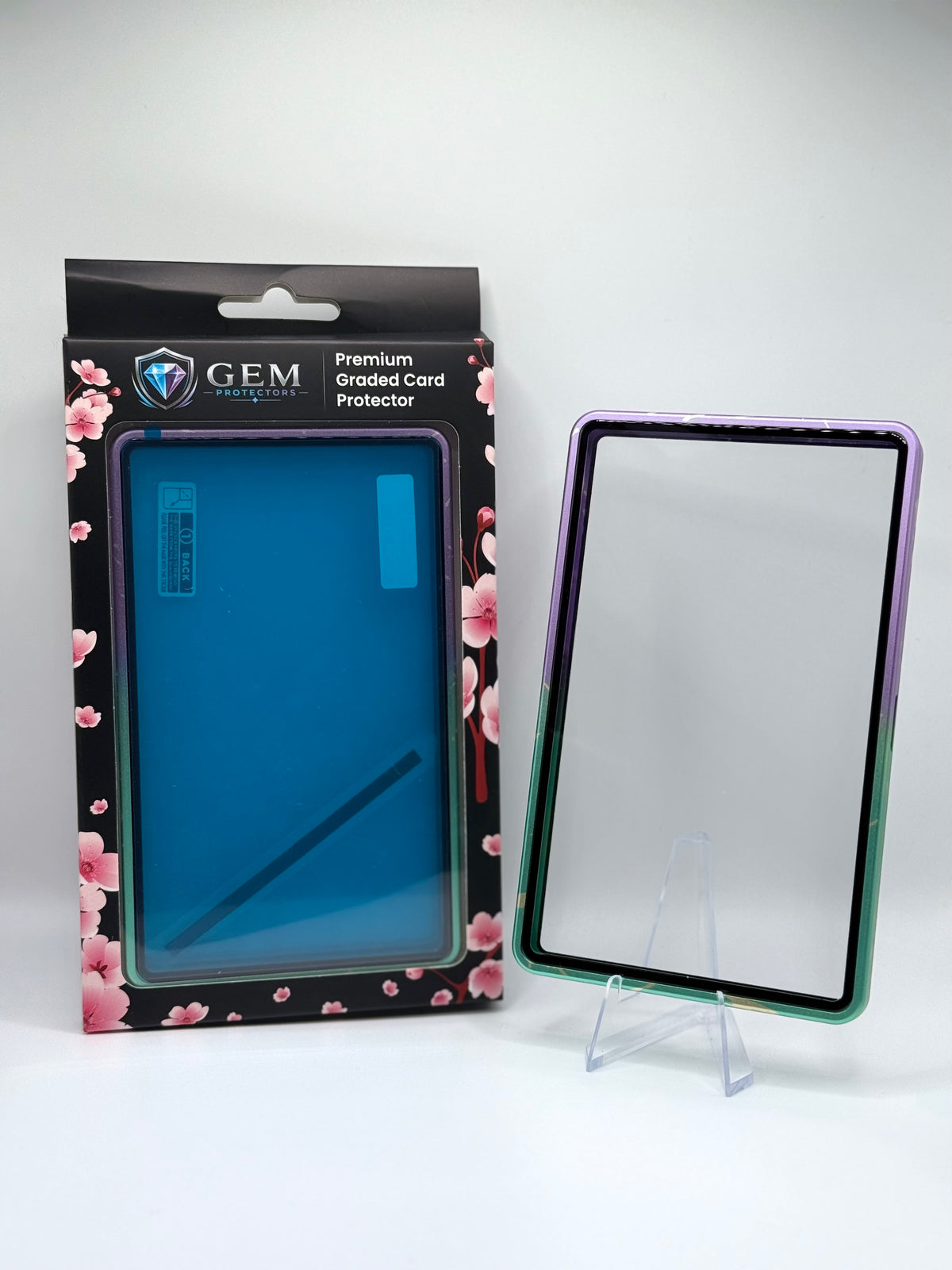 Front view of the empty Cyan & Purple Sparkle Gem Protectors case showing the frame and clear panel, beside its retail box