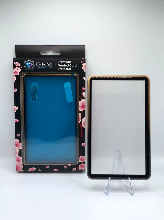 Black & Gold Speckle Gem Protectors magnetic PSA slab case standing upright on a clear stand next to its retail box