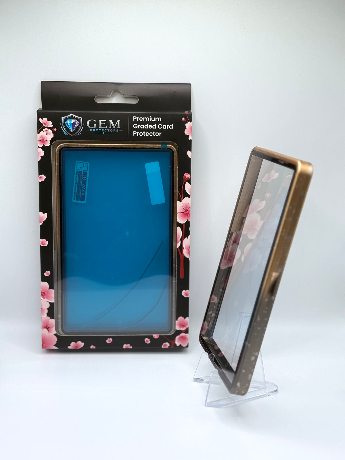 Black & Gold Speckle Gem Protectors case angled on a clear stand to show the frame's side profile, next to its retail box