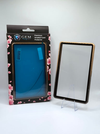 Front view of the empty Black & Gold Speckle Gem Protectors case showing the frame and clear panel, beside its retail box