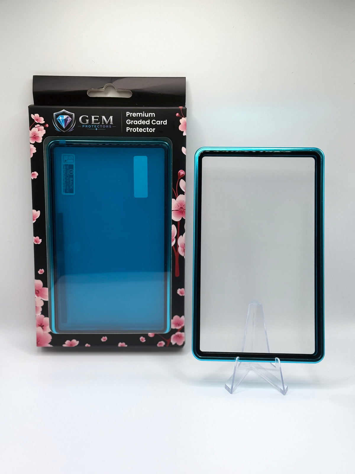 Teal Gem Protectors magnetic PSA slab case standing upright on a clear stand next to its retail box