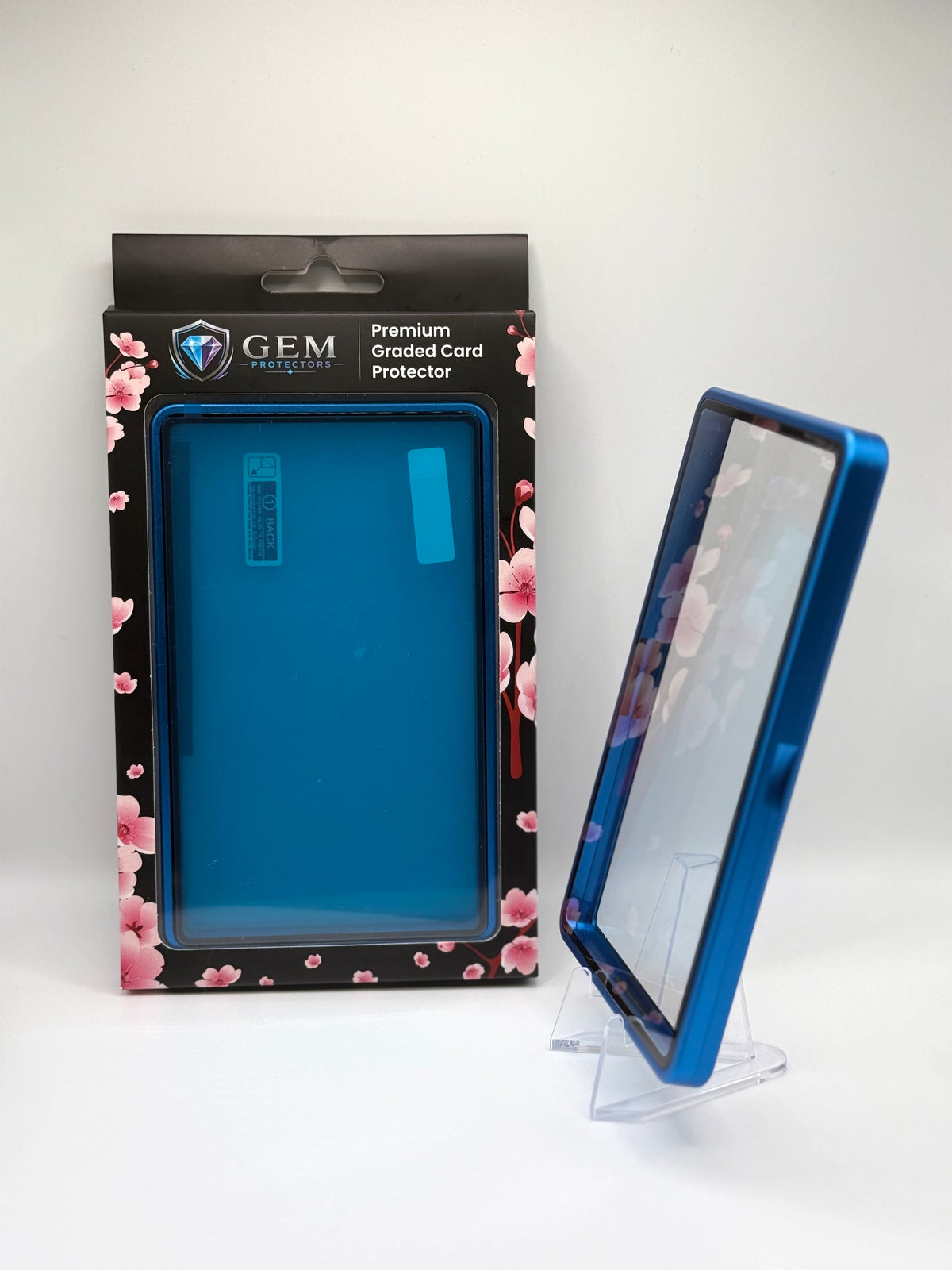 Deep Blue Gem Protectors case angled on a clear stand to show the frame's side profile, next to its retail box