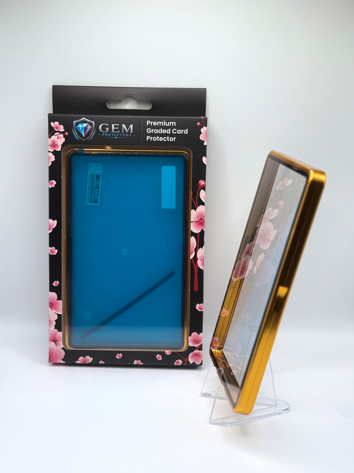 Gold Gem Protectors case angled on a clear stand to show the frame's side profile, next to its retail box