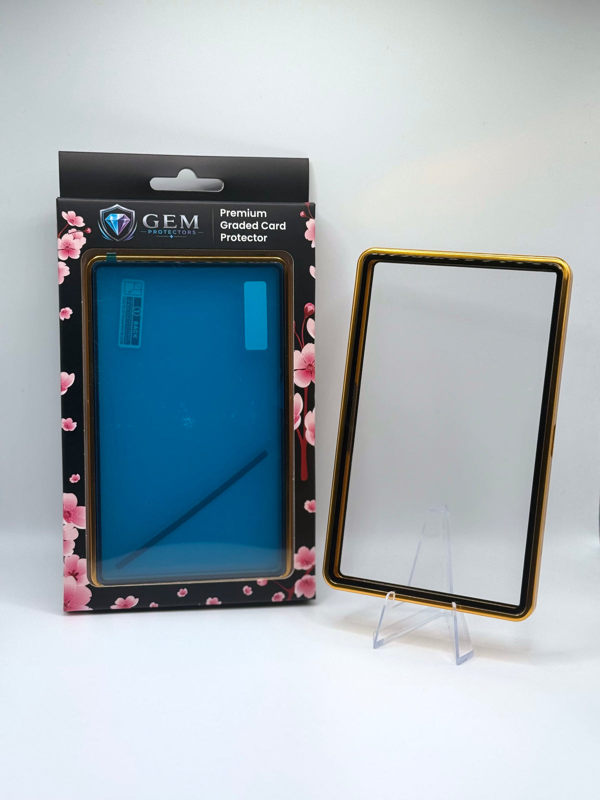 Front view of the empty Gold Gem Protectors case showing the frame and clear panel, beside its retail box