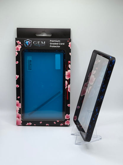 Blue Speckle Gem Protectors case angled on a clear stand to show the frame's side profile, next to its retail box