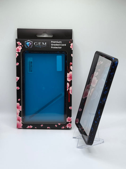 Blue Speckle Gem Protectors case angled on a clear stand to show the frame's side profile, next to its retail box