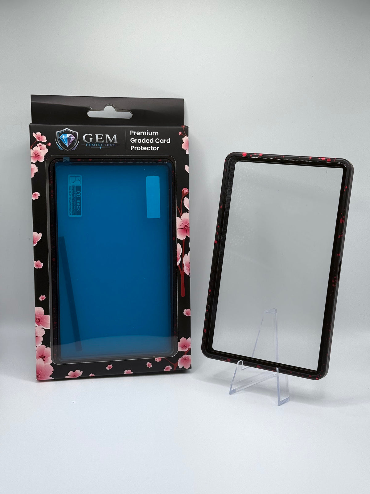 Front view of the empty Red Speckle Gem Protectors case showing the frame and clear panel, beside its retail box